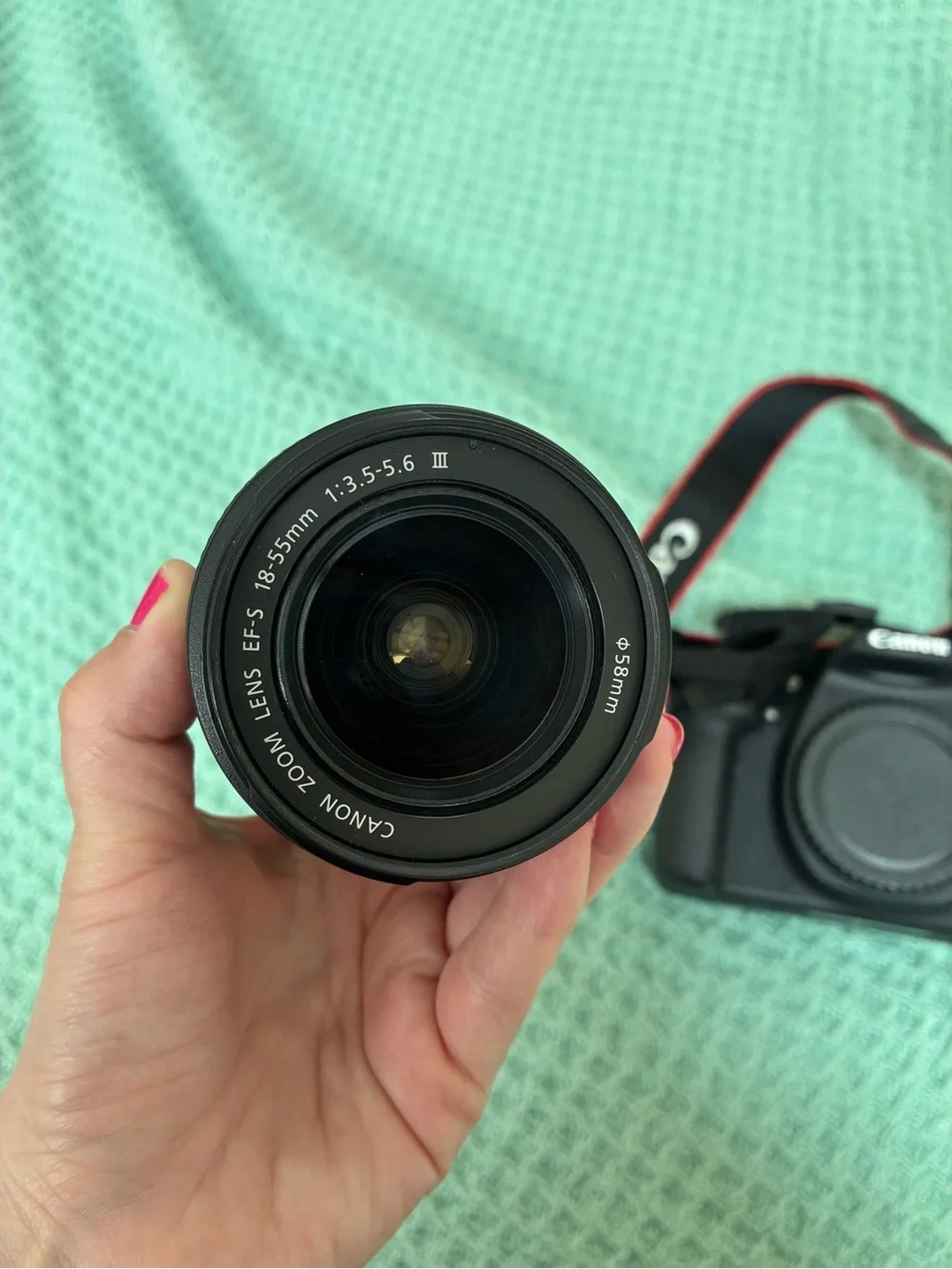 Canon DSLR Camera Body in Black with Red Strap Accents and kit lens.